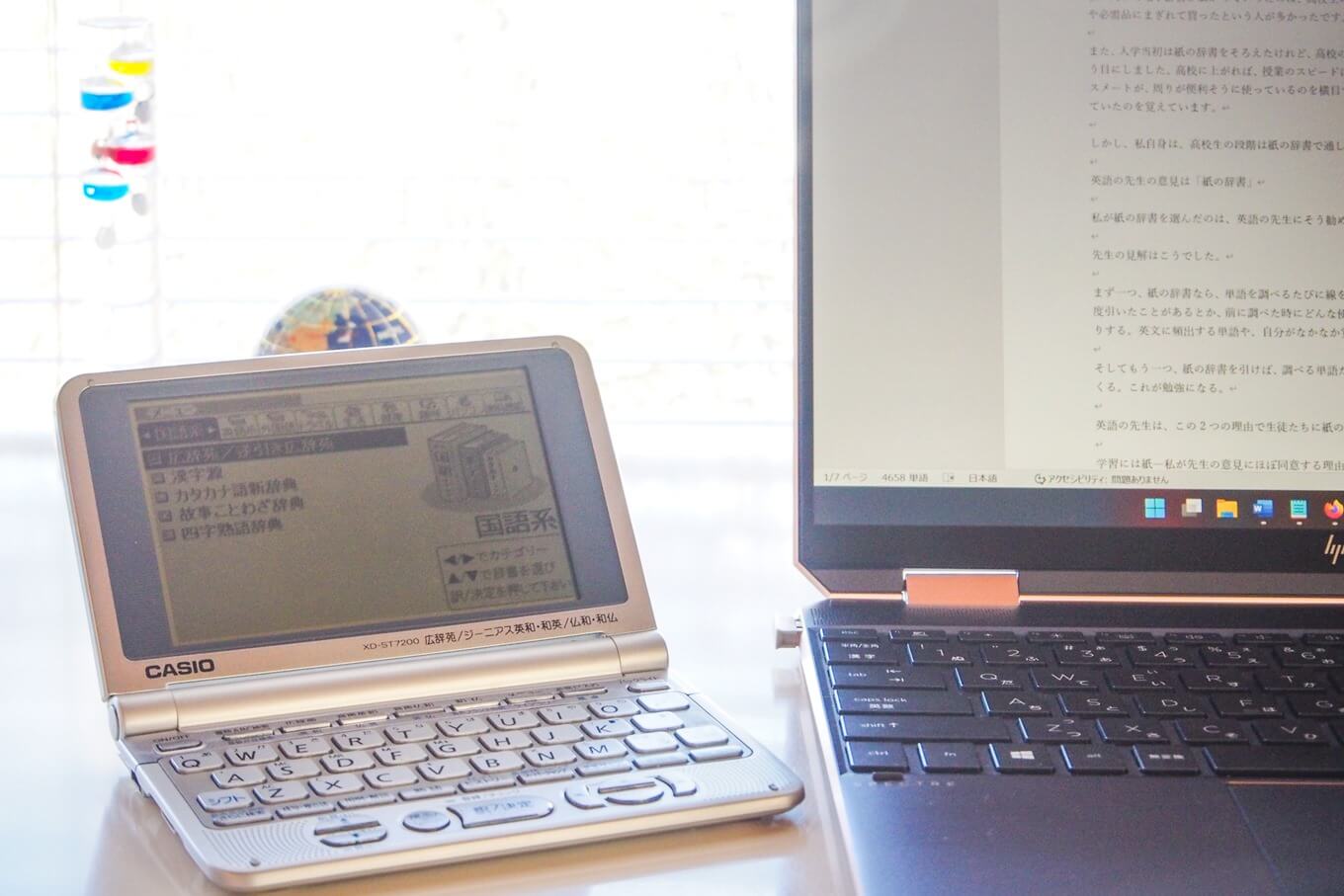 ノートパソコンと電子辞書が置いてあるデスクの写真